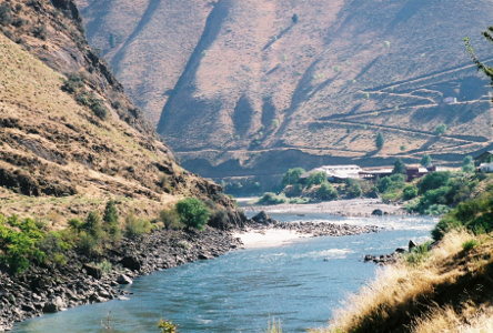 [The river comes around the mountain from the left into the center of the image. The hillside behind the river has a series of switchbacks going up the hill.]